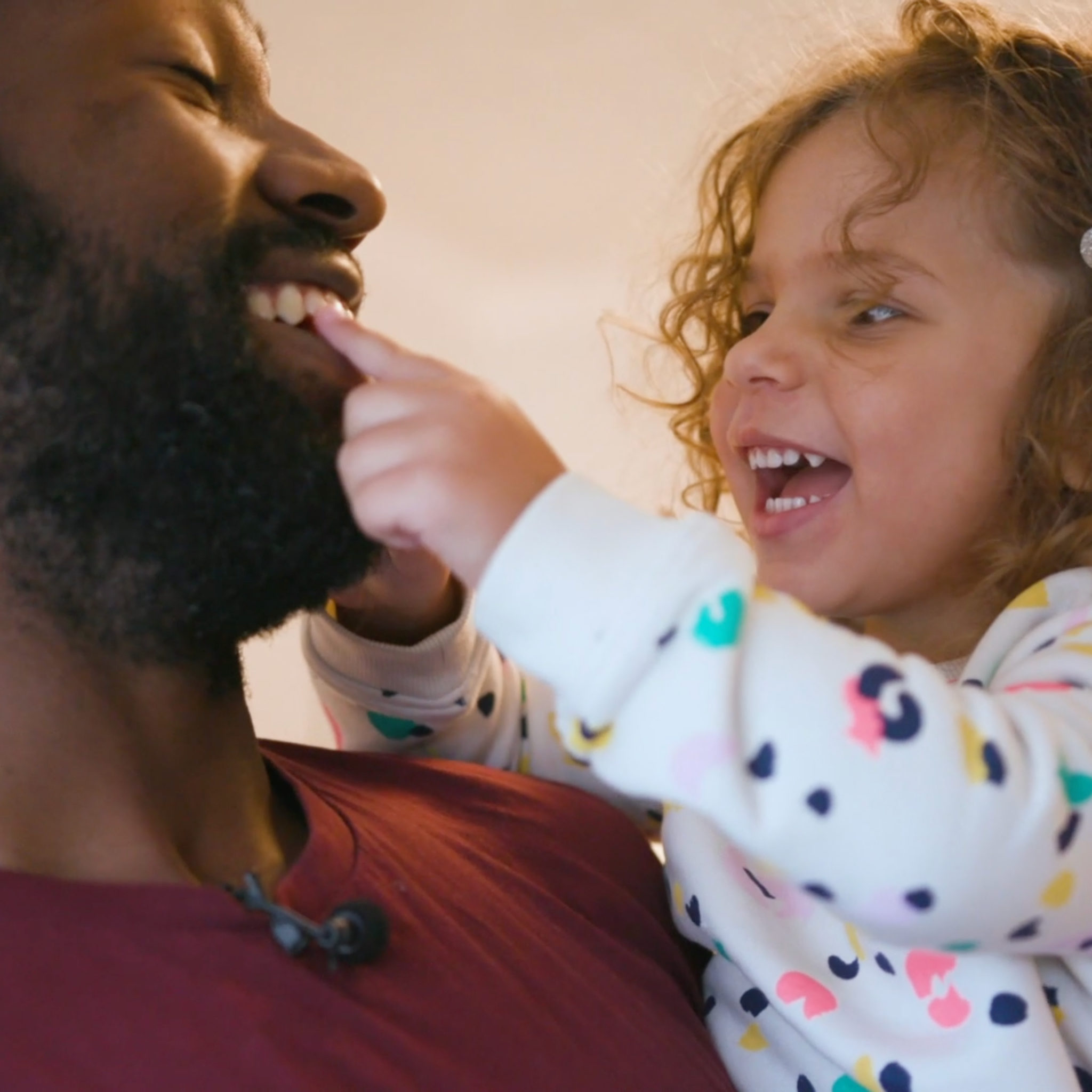 A dad and daughter smiling as they play