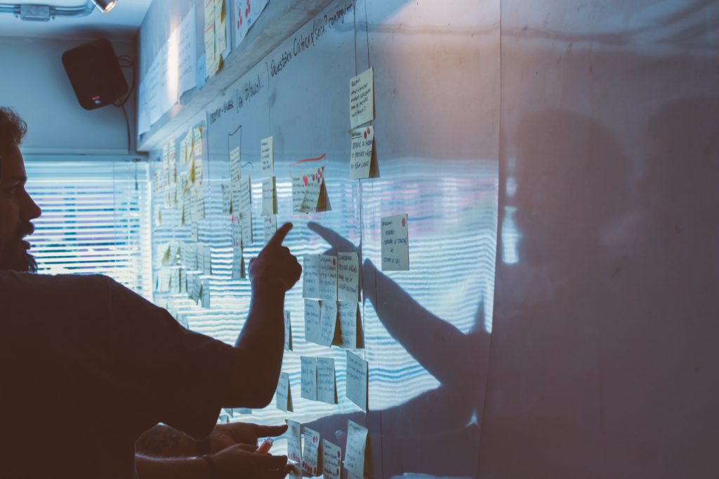 A man pointing at post-it notes on an office whiteboard