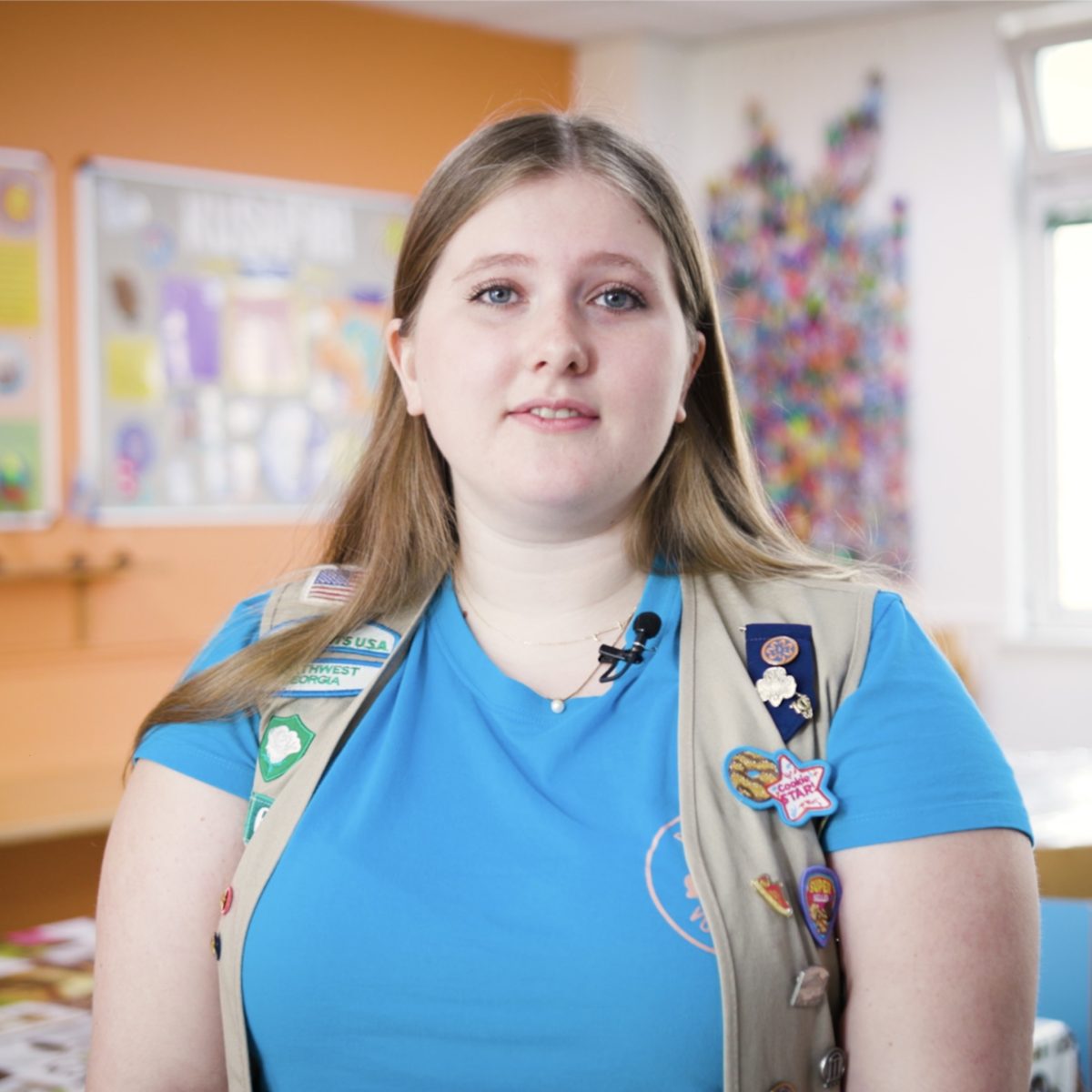 A Girl Guide wearing a tabard with several badges on it