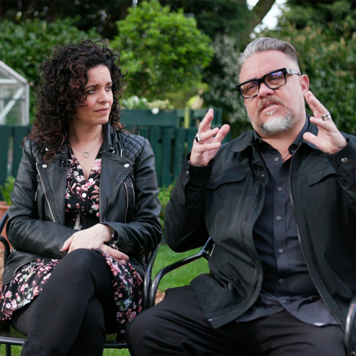 A woman and a man sitting in a garden.