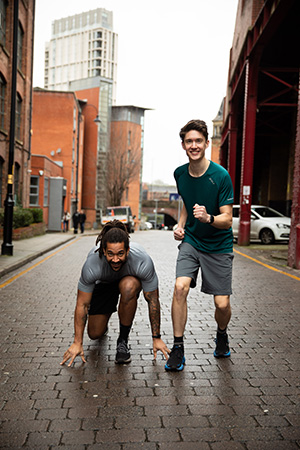 Ben and Jamie on a city street, wearing running clothes, training to run a half marathon for St Ann's Hospice.