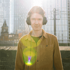 Animated GIF of a man taking headphones off, as a yellow tram moves past him in the background