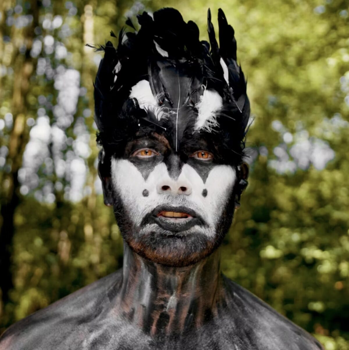 Dramatic close-up photo of a man wearing clown-like magpie make-up.