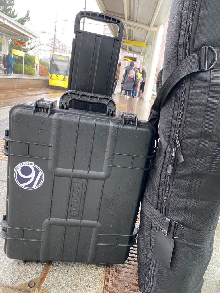 Camera bags with Studio 91 Media logo, at a Metrolink tram stop