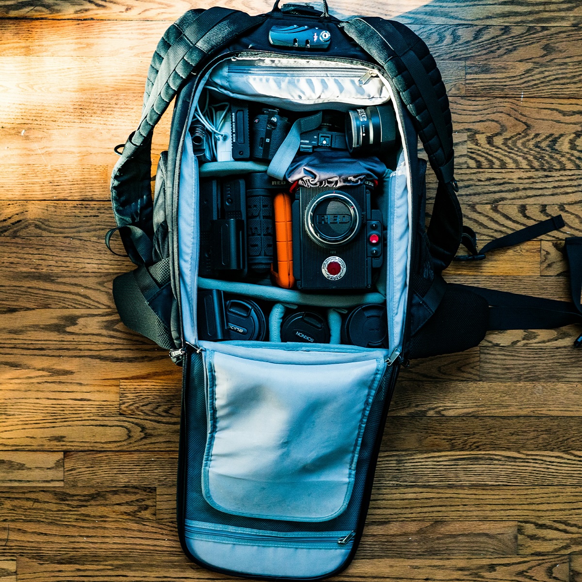 Top view of an open camera kit bag containing various lenses and other camera tools