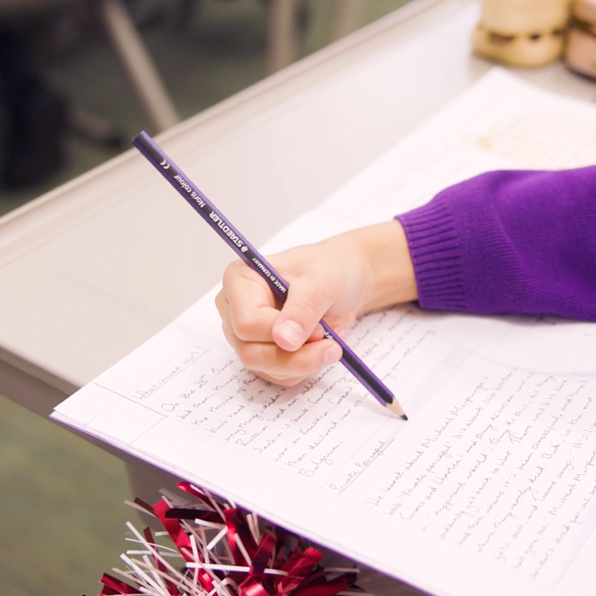 Screenshot from a fundraising film showing a close-up of a girl writing in an exercise book at primary school